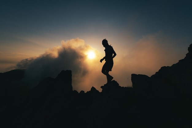 A man in silhouette at sunset walks a rocky ridge during a solitary meditation