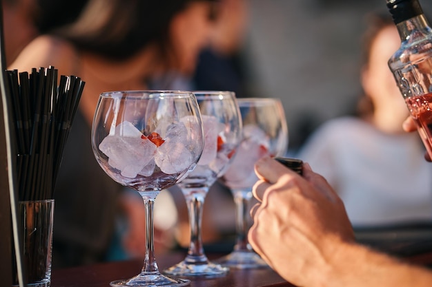 A man sits at a bar with wine glasses and a bottle of wine.