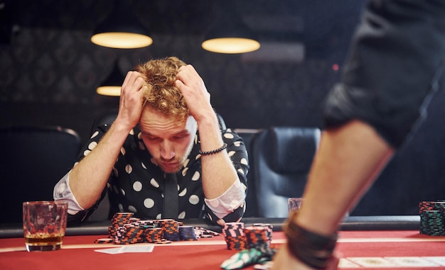 Photo man sits in casino and feels bad because losing poker game