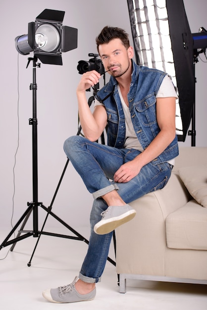 A man sits on the couch with a camera in his hands.