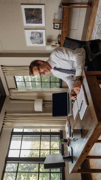 Photo a man sits at a desk in a room with a laptop and a lamp