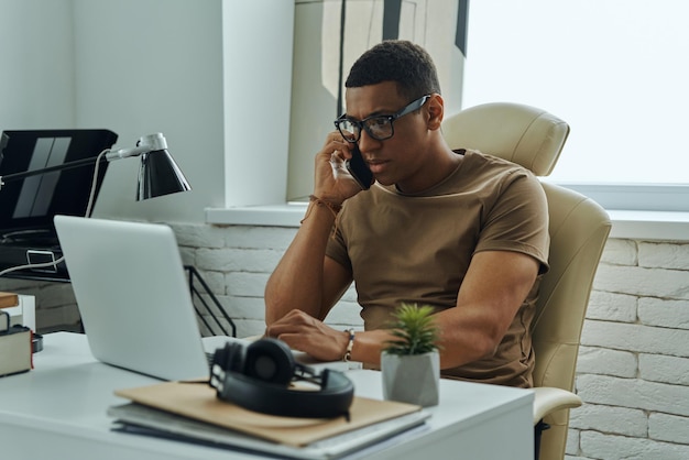 a man sits at a desk and talks on a phone