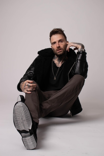 A man sits on the floor wearing a black jacket and black pants.