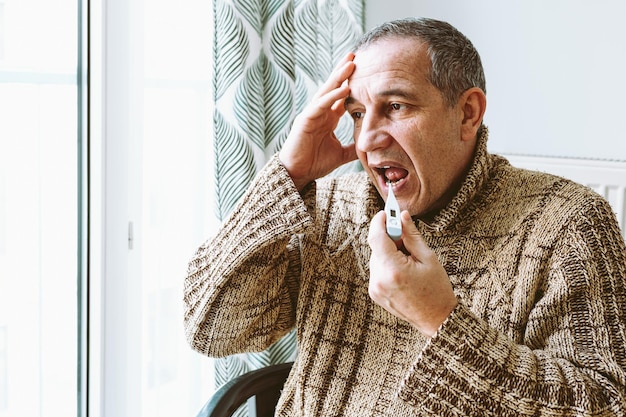 A man sits in front of a window with a device that says'smoke'on it.