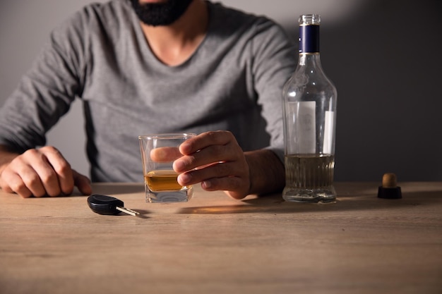 A man sits holding an alcoholic drink in his hand Car keys