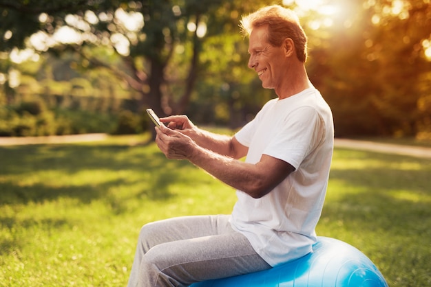 A man sits in a park on a blue bowl for yoga.