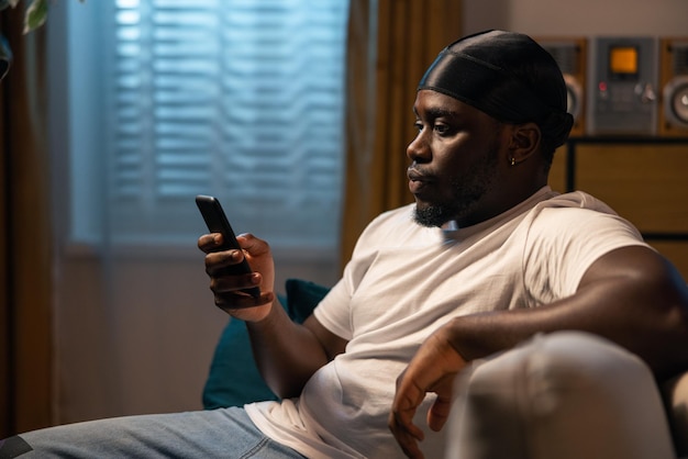 A man sits on the sofa with a smartphone in hand in spare time browsing store websites