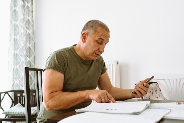 A man sits at a table with a calculator and looks at a calculator.