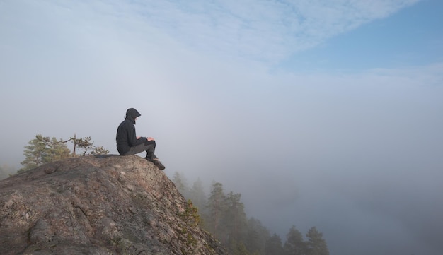 A man sits on top of a granite mountain atmospheric hazy view