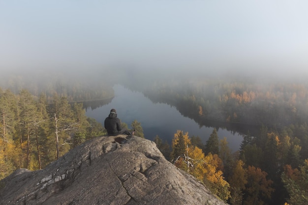 A man sits on top of a granite mountain Atmospheric hazy view