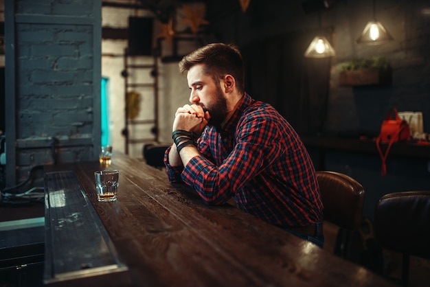 Photo man sitting at the bar counter and drink alcohol