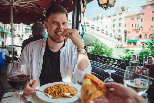 Man sitting in cafe eating pasta drinking wine rialto bridge on background venice italy outdoors restaurant