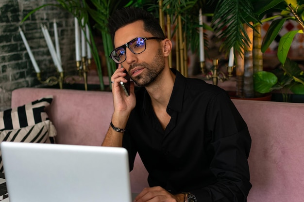 man sitting in cafe with phone, laptop and coffee