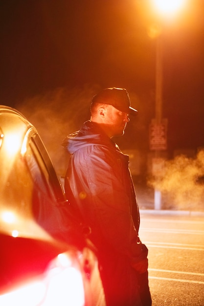 Man sitting next to car at night