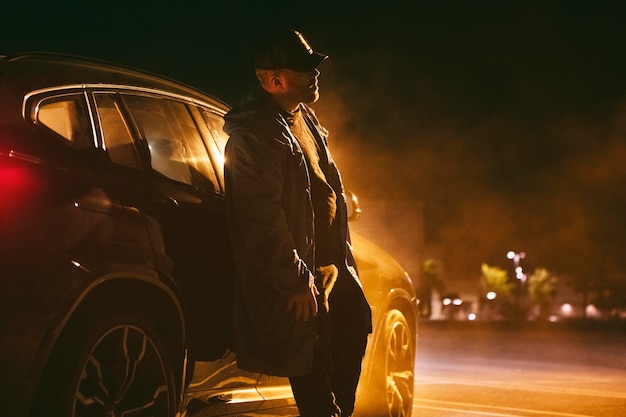 Man sitting next to car at night