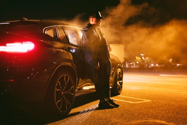 Man sitting next to car at night