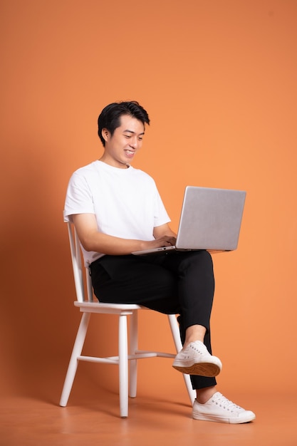 Man sitting on chair isolated on orange background