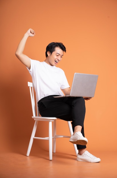 Man sitting on chair isolated on orange background