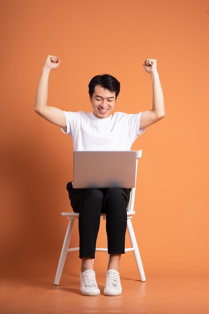 Man sitting on chair isolated on orange background