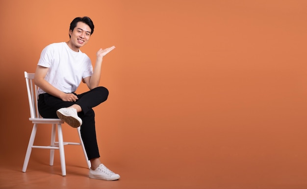 Man sitting on chair isolated on orange background