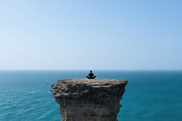 a man sitting on a cliff overlooking the ocean