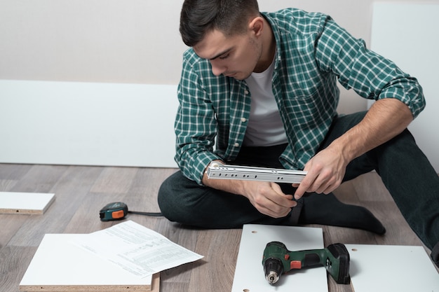 man sitting on the floor of room with tools collect furniture according to instructions