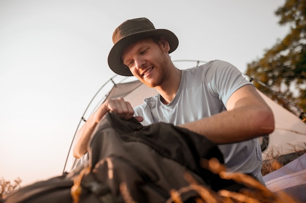 A man sitting on the ground and packing his backpack