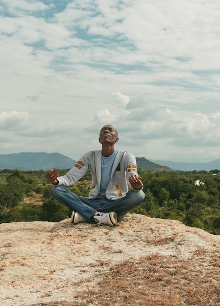 Photo a man sitting on a hill top meditating