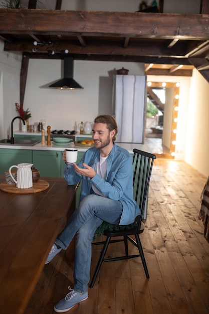 A man sitting in his kitchen and drinking tea