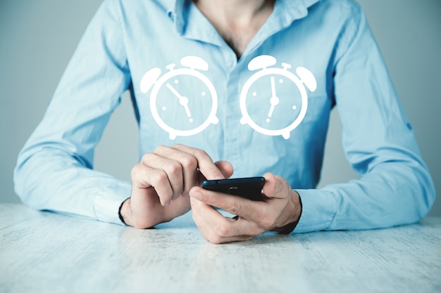 Photo a man sitting holds a phone. alarm clock concept