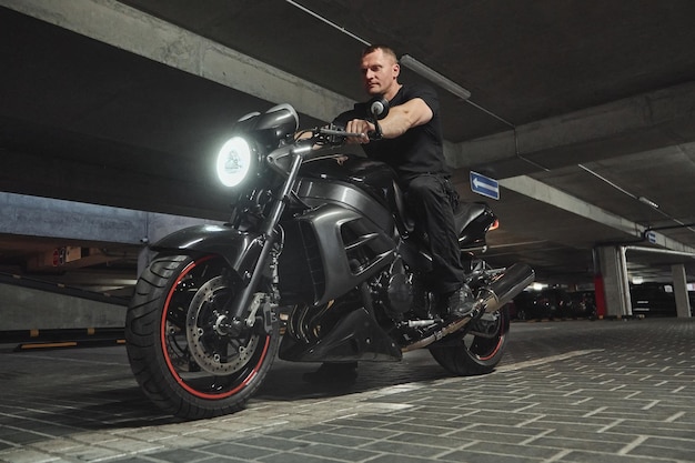 A man sitting on motorcycle in underground parking garage