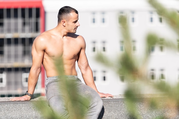 Man Sitting on Old Rooftop Strong and Posing