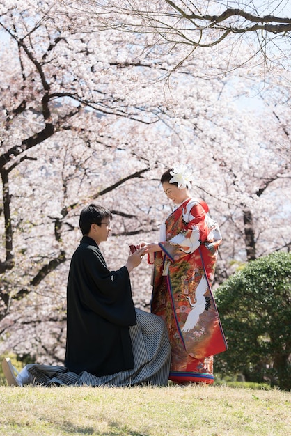 Man sitting on one knee proposing to woman in park