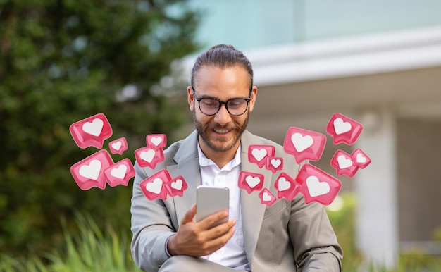 Photo man sitting outdoors smiling while checking his phone