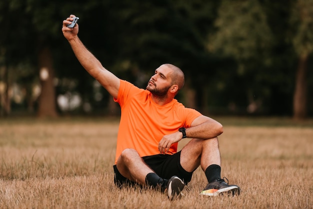 A man sitting in park and making a selfie after finishing his morning training