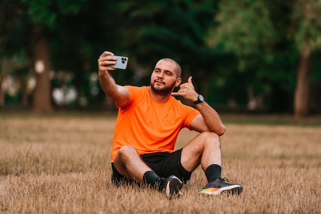 A man sitting in park and making a selfie after finishing his morning training