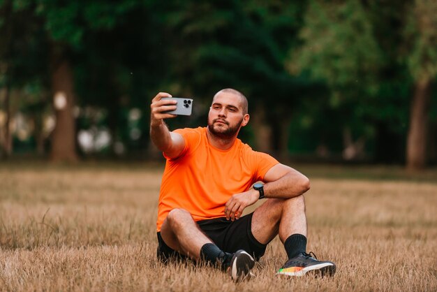 A man sitting in park and making a selfie after finishing his morning training