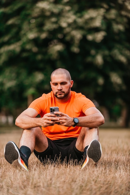 A man sitting in park and using smartphone after finishing his morning training