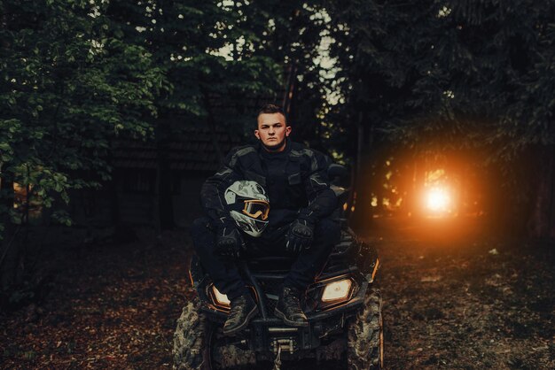 Man sitting on quad in forest and preparing for ride