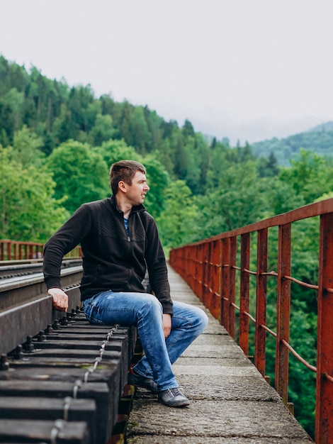 Man sitting on a railway bridge in the woods