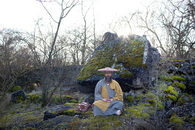 Photo man sitting on rock against trees