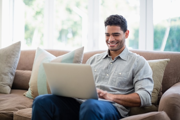 Man sitting on sofa and using laptop in living room