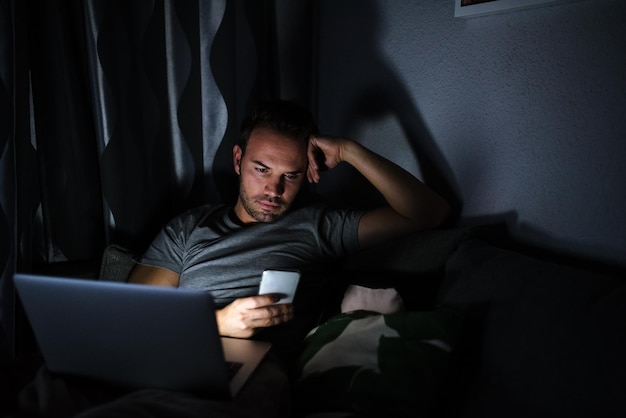 Man sitting on the sofa with a mobile phone and computer