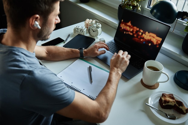 Man sitting at table by the window and using laptop