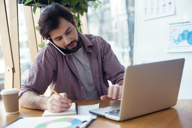 Man sitting at the table at creative stylish office multitasking