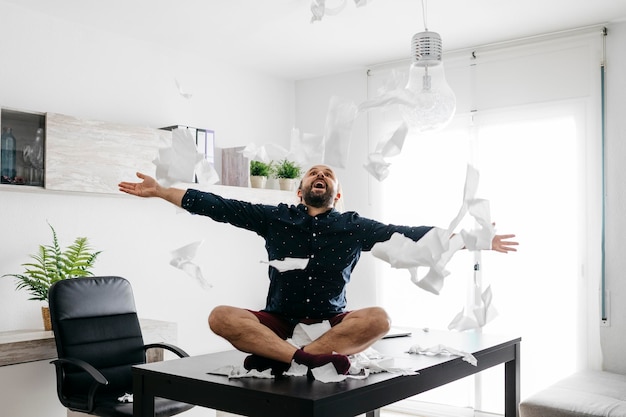 Photo man sitting on top of a table playing with toilet paper