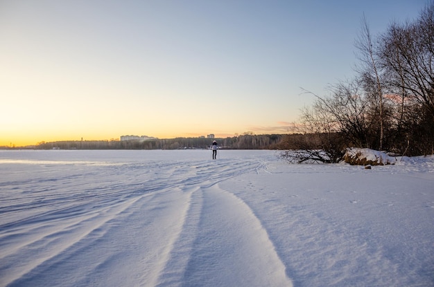 A man skiing on a frozen lake with a sunset in the background