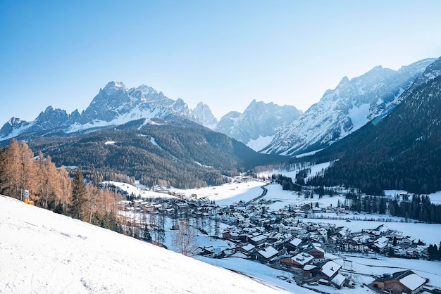 Man skiing with snow covered house and mountain in background during winter