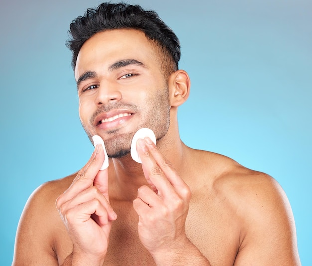 Man skincare portrait and cotton pad in studio for beauty wellness or cosmetic self care with smile Happy model face and cottonwool for cleaning cosmetics or healthy aesthetic by blue background