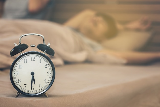 Man sleeping without waking up in the morning with alarm clock on workday.